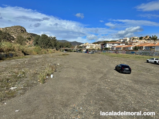 cauce del río Totalán junto al aparcamiento de autocaravanas en La Cala del Moral con vegetación y entorno natural.